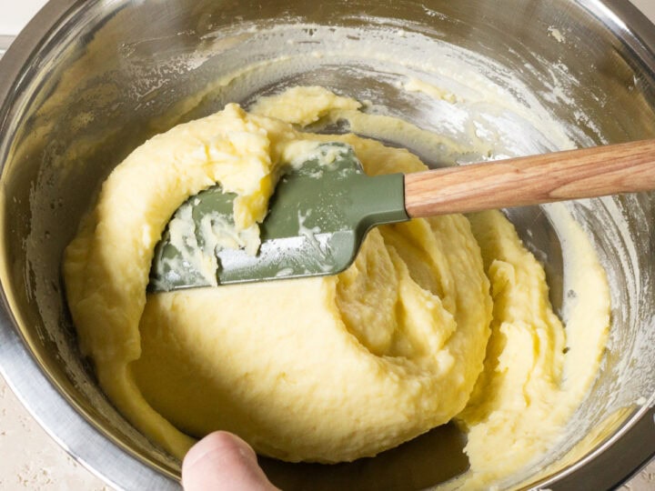 Mashed potatoes and cream being folded in a large bowl.