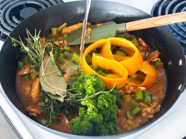 Fish stock is added to prawn shells cooked with tomato paste and fennel, fresh parsley, thyme and bay leaves and orange peel.