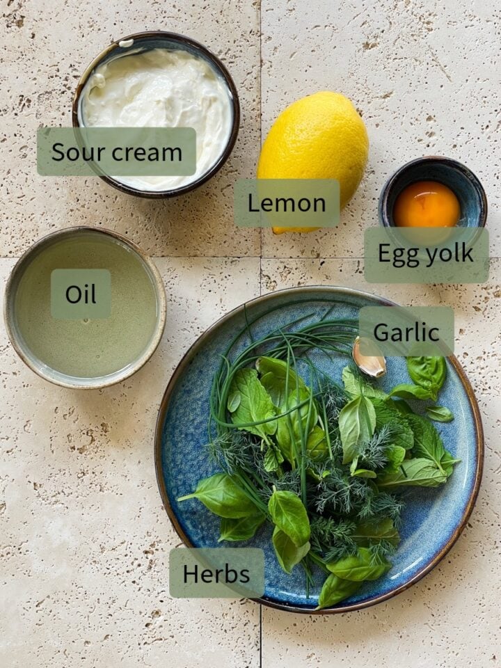 Ingredients for creamy herb dressing from top: sour cream, lemon, egg yolk, oil, garlic and herbs.