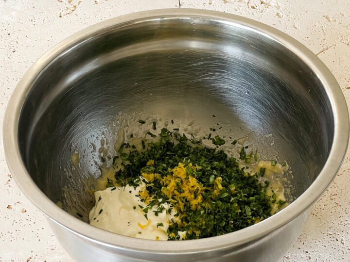 Mixed chopped herbs, lemon zest, crushed garlic and sour cream added to the bowl with mayonnaise in it.