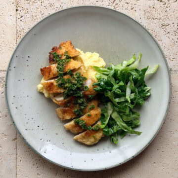 Crispy chicken cotoletta topped with salsa verde and served with creamy mashed potatoes and shredded cos salad.