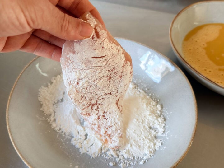 Chicken cutlet coated in cornflour for cooking preparation.
