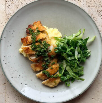 Crispy chicken cotoletta topped with salsa verde and served with creamy mashed potatoes and fresh cos salad.