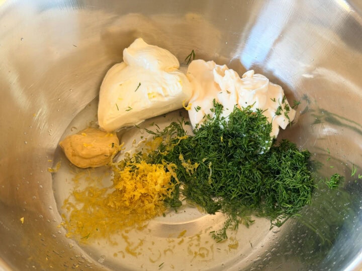Fresh dill, dijon mustard, sour cream, mayonnaise, lemon juice and zest in a mixing bowl.