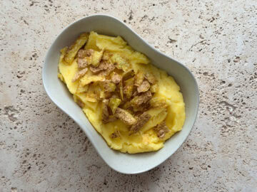 Rosemary mashed potatoes topped with crispy potato skins served in an irregular shaped bowl.