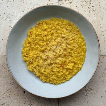 A bowl of saffron risotto topped with grated Parmesan cheese