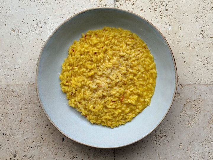 A bowl of saffron risotto topped with grated Parmesan cheese