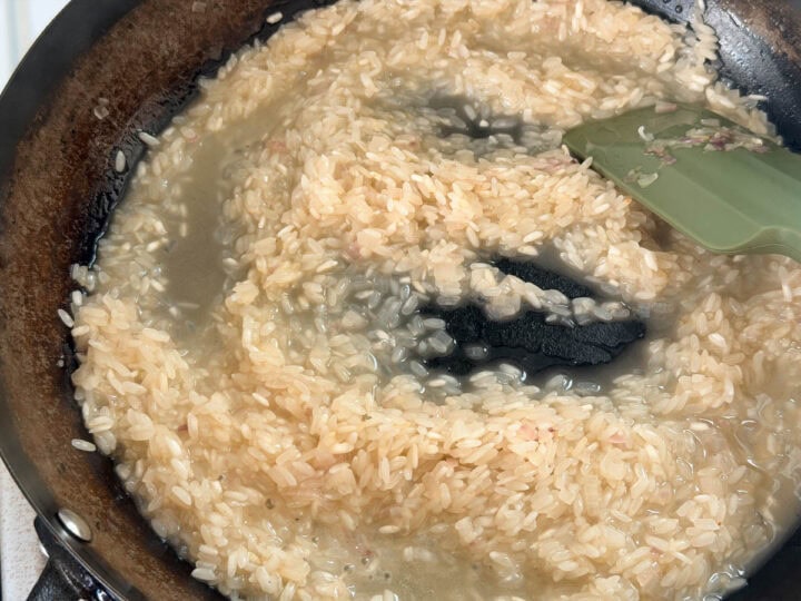 White wine is added to arborio rice and shallots and simmered.