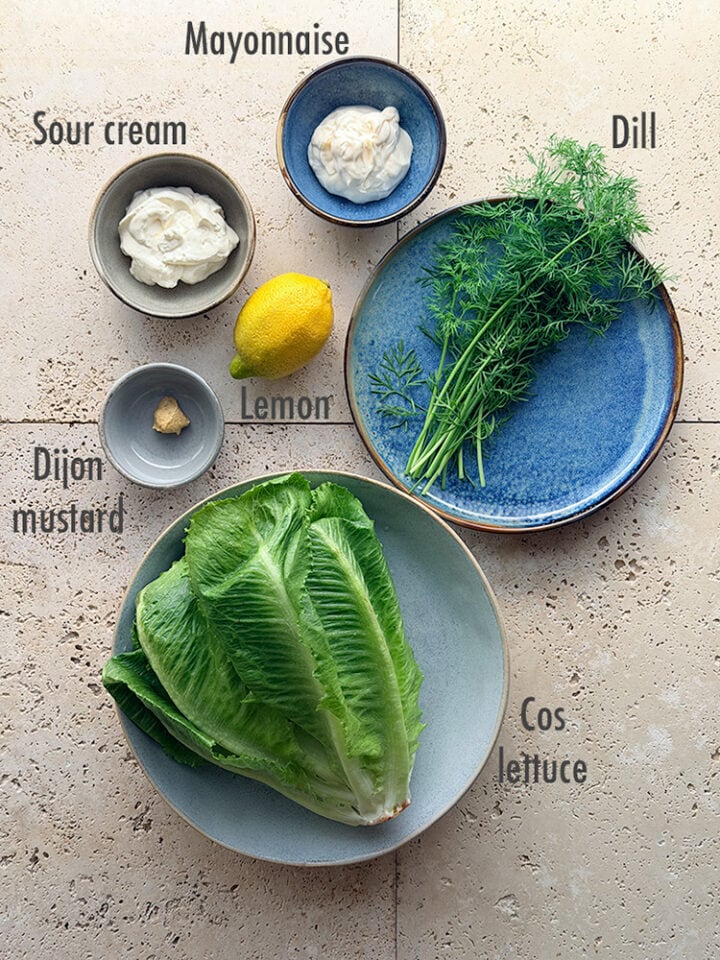 Ingredients for cos salad with creamy dill dressing: mayonnaise, sour cream, lemon, dijon mustard, dill and cos lettuce.