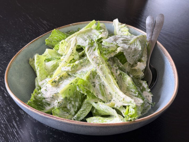 Fresh Caesar salad with romaine lettuce and creamy dressing in a ceramic bowl.